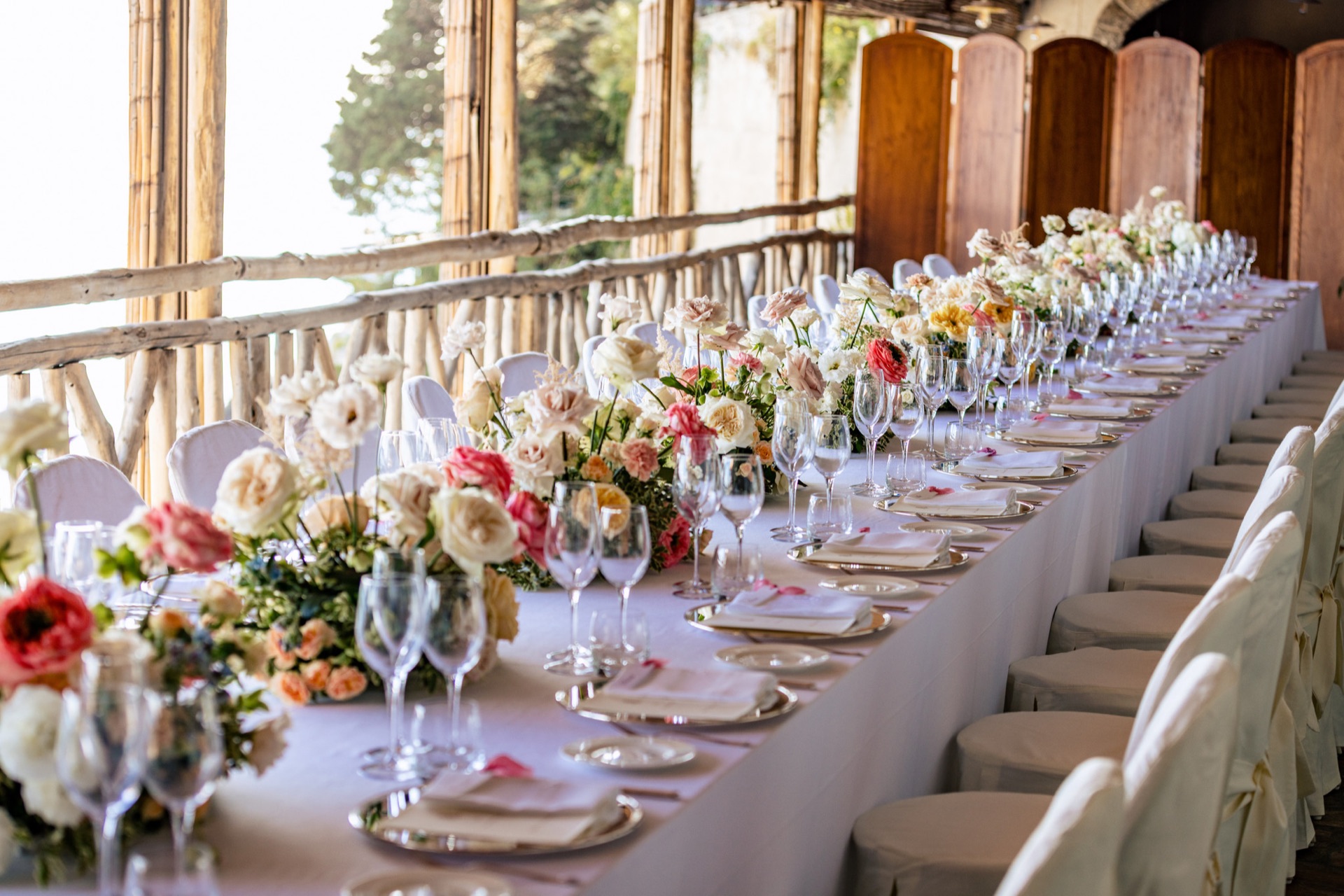 Roses, glassware and pale plates on an Amalfi Coast wedding table