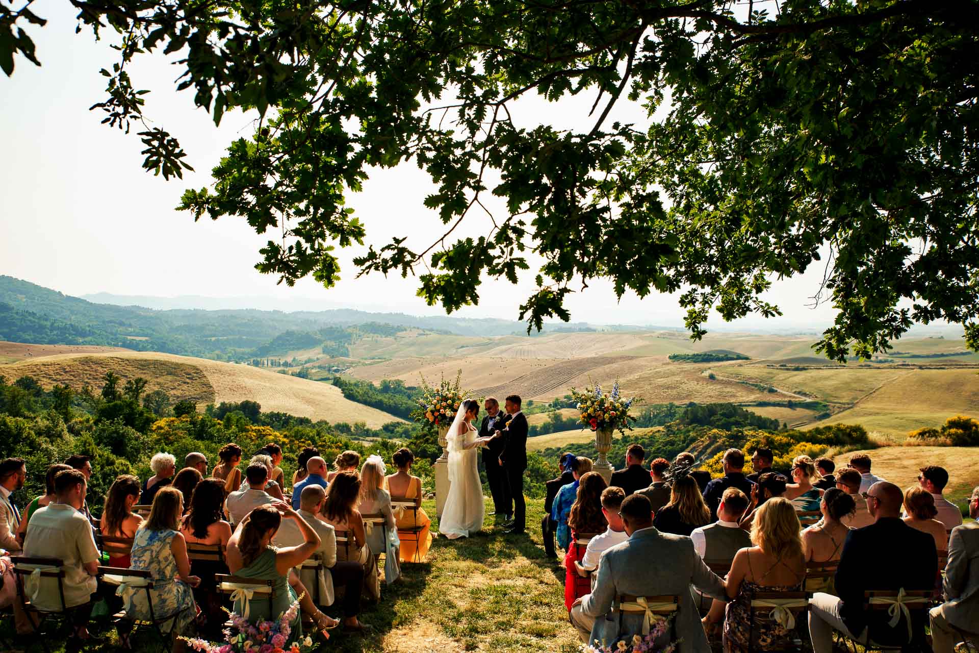 An outdoor wedding ceremony beneath a tree in the Tuscan countryside